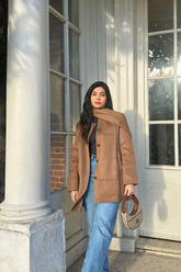 a lady in a black top, a brown wool coat and a pair of blue jeans